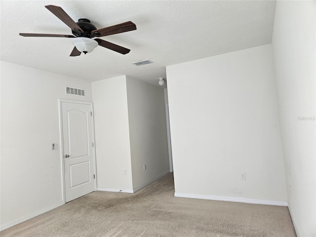 unfurnished room featuring light carpet, ceiling fan, and a textured ceiling