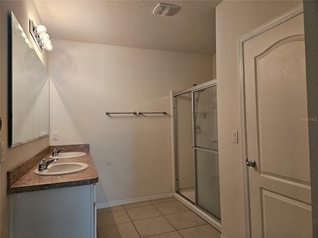 bathroom featuring tile patterned flooring, a textured ceiling, vanity, and walk in shower