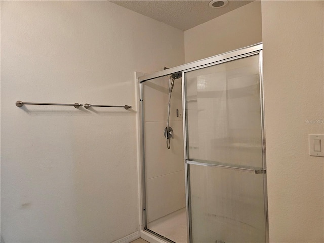 bathroom featuring a textured ceiling and a shower with shower door