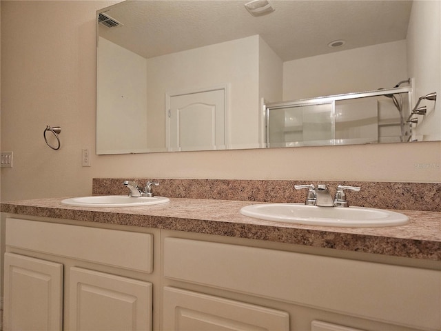 bathroom featuring vanity, a shower with shower door, and a textured ceiling