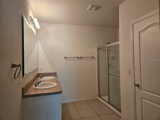 bathroom with tile patterned flooring, a textured ceiling, vanity, and a shower with shower door