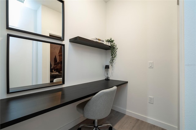 office space with built in desk and wood-type flooring