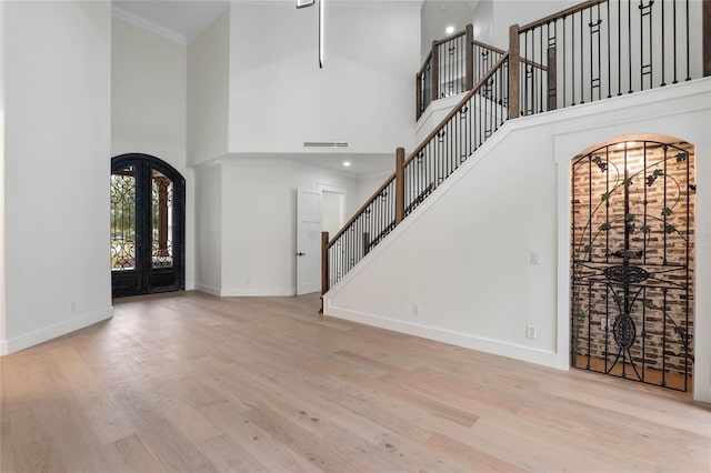 foyer featuring a high ceiling, light hardwood / wood-style floors, and french doors