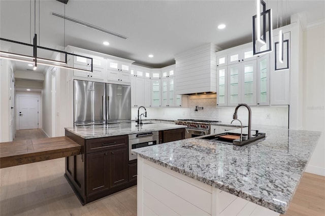 kitchen with pendant lighting, light stone countertops, stainless steel appliances, and white cabinets