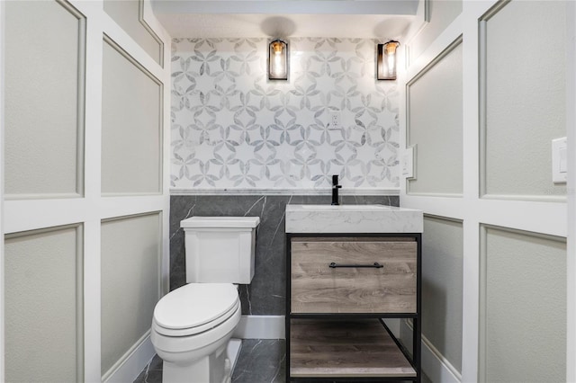 bathroom featuring vanity, toilet, and tile walls