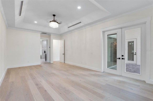 empty room with french doors, a tray ceiling, and light hardwood / wood-style flooring