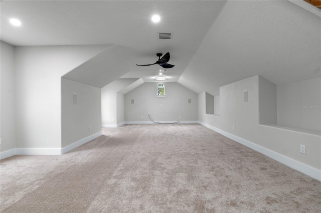 bonus room with vaulted ceiling, light colored carpet, a textured ceiling, and ceiling fan