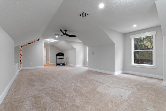 bonus room with ceiling fan, lofted ceiling, light colored carpet, and a textured ceiling