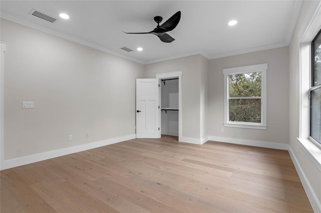 unfurnished bedroom featuring multiple windows, a spacious closet, crown molding, and ceiling fan