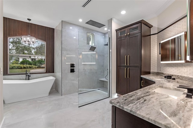 bathroom with an inviting chandelier, ornamental molding, vanity, and separate shower and tub