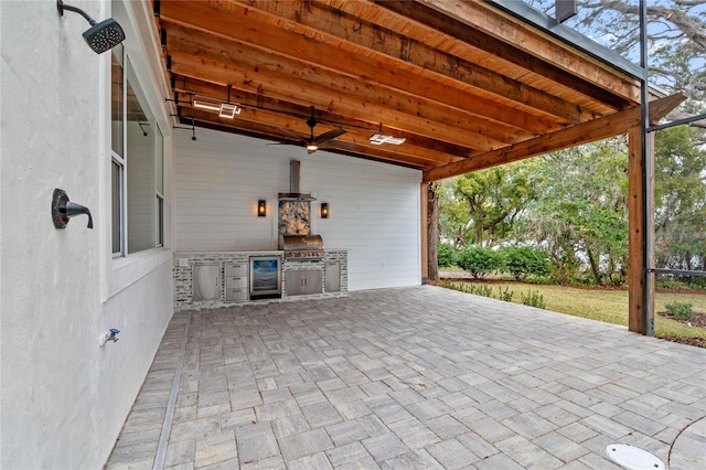 view of patio / terrace with grilling area, beverage cooler, ceiling fan, and an outdoor kitchen