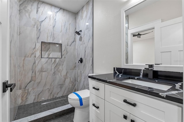 bathroom featuring vanity, toilet, and a tile shower