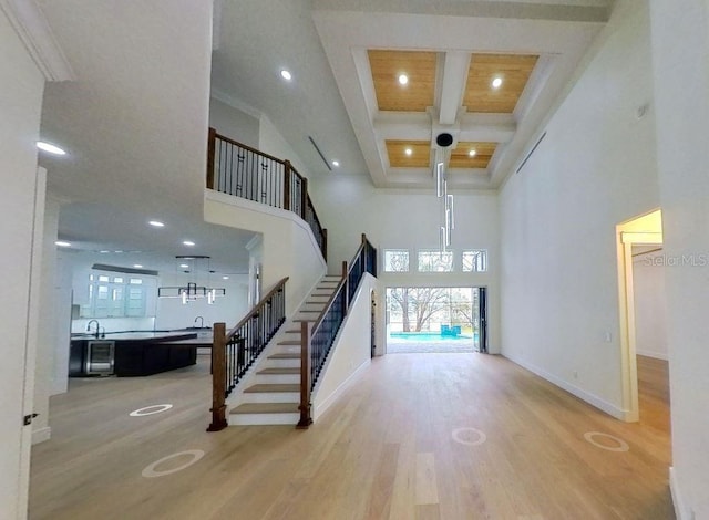 foyer with hardwood / wood-style floors, beamed ceiling, a high ceiling, coffered ceiling, and crown molding