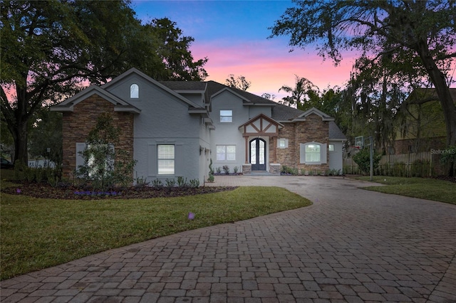 view of front of property with a front lawn, decorative driveway, fence, and french doors