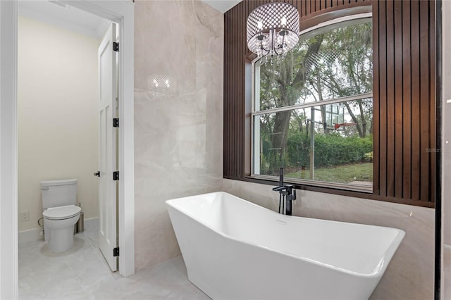 full bathroom with an inviting chandelier, toilet, and a freestanding bath