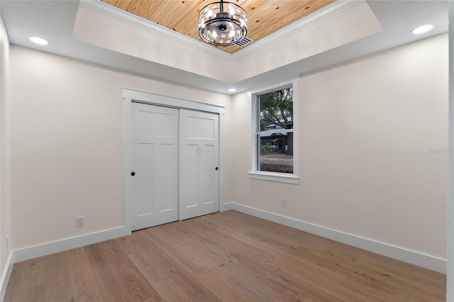 unfurnished bedroom featuring baseboards, a tray ceiling, light wood-style floors, wooden ceiling, and a chandelier