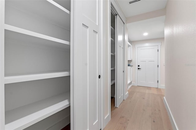 corridor featuring recessed lighting, baseboards, and light wood-style floors