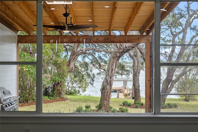 interior space featuring wooden walls, a ceiling fan, and a water view