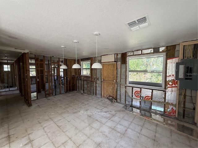 miscellaneous room featuring electric panel, a textured ceiling, and a wealth of natural light