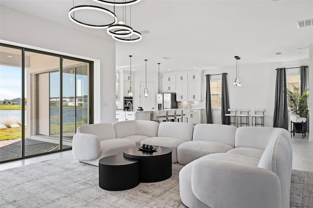 living room featuring a chandelier, a water view, and light hardwood / wood-style flooring