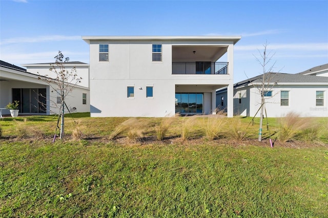 back of property with a yard and a balcony