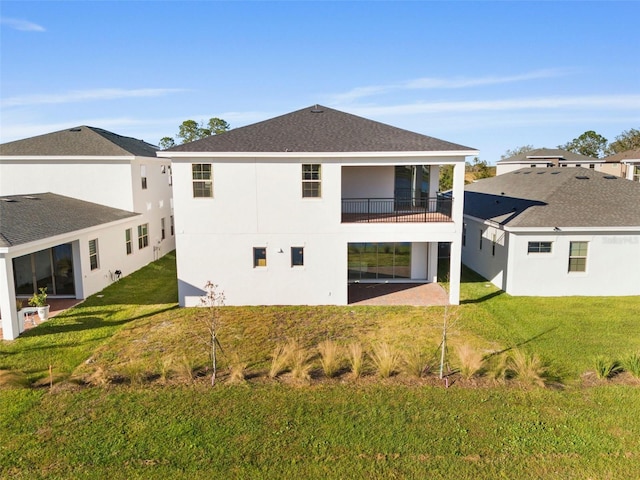 rear view of house featuring a balcony and a lawn