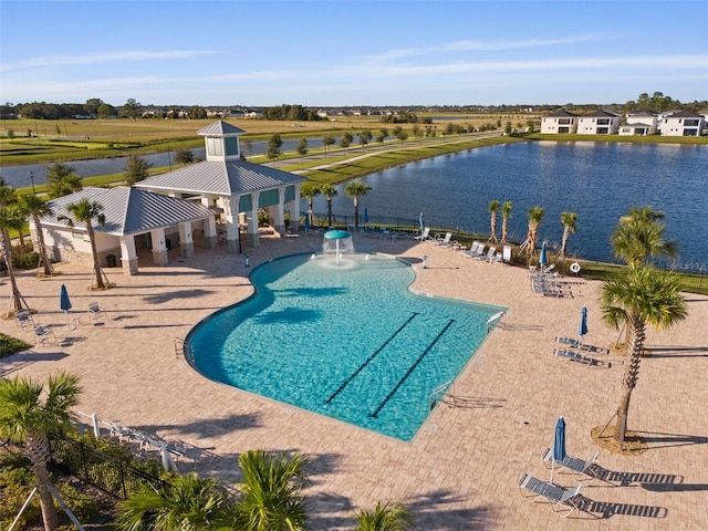 view of swimming pool with pool water feature, a water view, and a patio