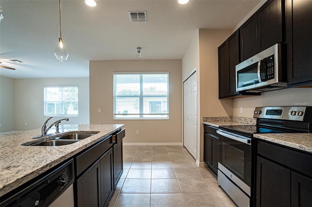 kitchen featuring light tile patterned flooring, appliances with stainless steel finishes, light stone counters, and sink