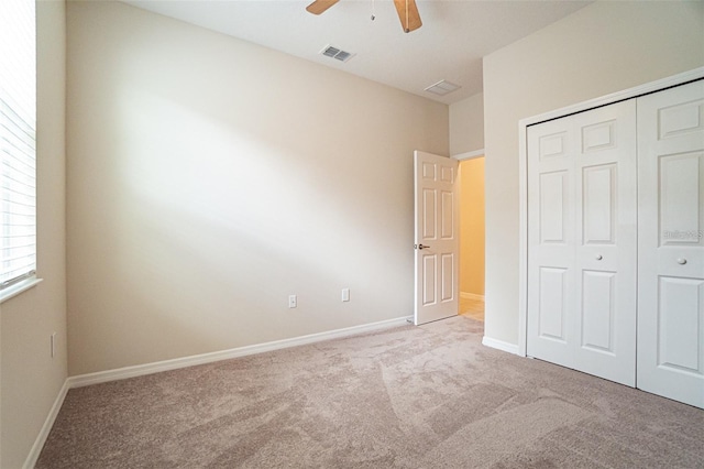 unfurnished bedroom featuring ceiling fan, a closet, and light carpet