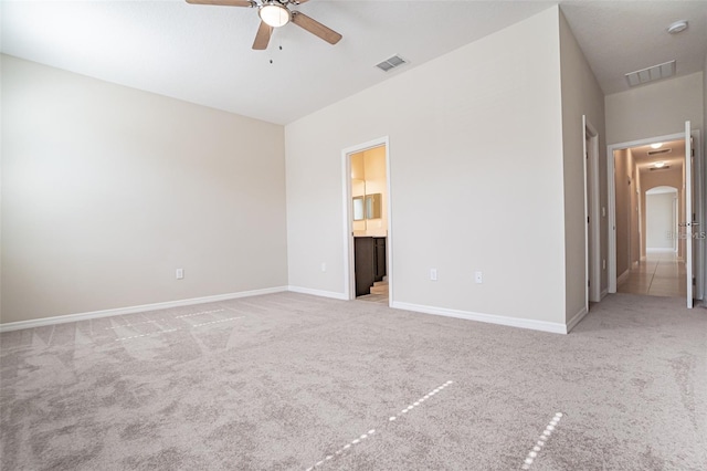 unfurnished bedroom with connected bathroom, light colored carpet, and ceiling fan