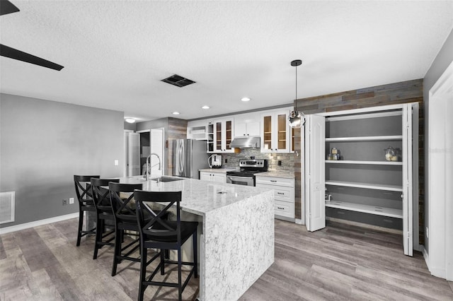 kitchen featuring white cabinetry, stainless steel appliances, hardwood / wood-style floors, pendant lighting, and a breakfast bar