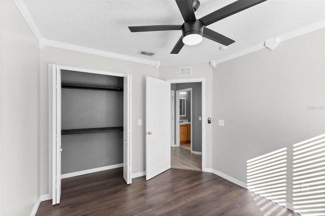 unfurnished bedroom with crown molding, ceiling fan, dark hardwood / wood-style floors, a textured ceiling, and a closet