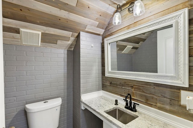 bathroom featuring brick wall, lofted ceiling, toilet, vanity, and wood ceiling