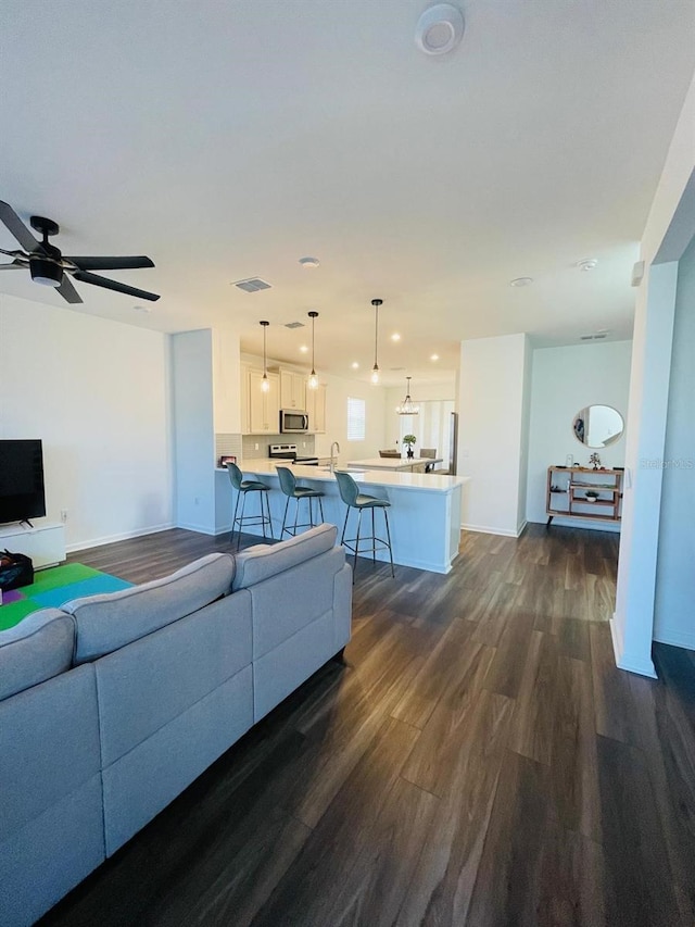 living room with ceiling fan, dark hardwood / wood-style flooring, and sink