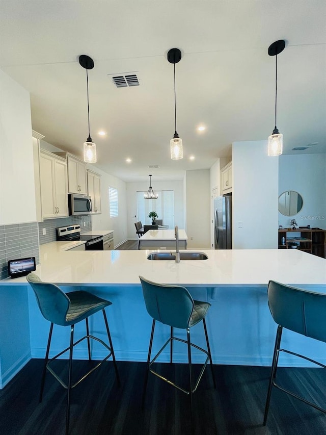 kitchen featuring kitchen peninsula, appliances with stainless steel finishes, dark hardwood / wood-style flooring, sink, and white cabinets