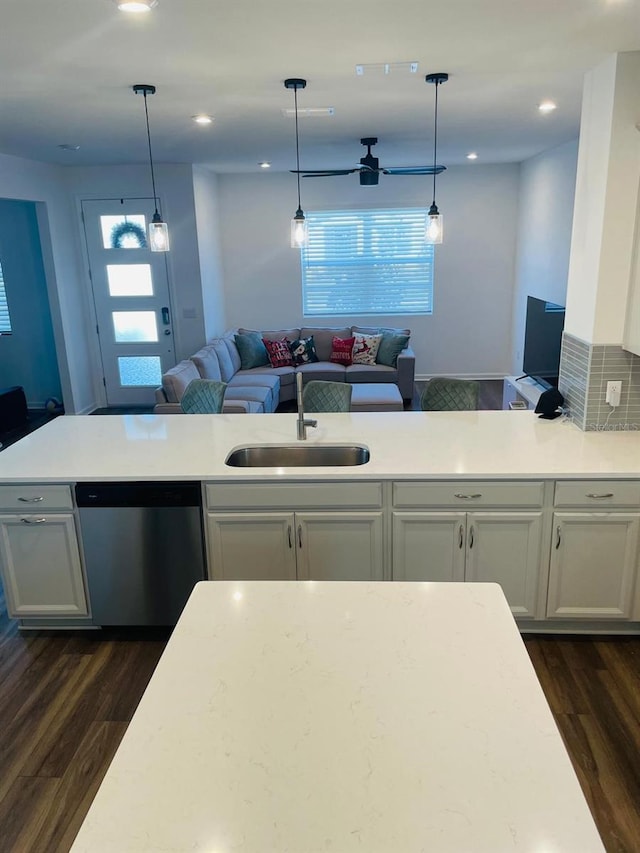 kitchen with stainless steel dishwasher, hanging light fixtures, dark wood-type flooring, and sink