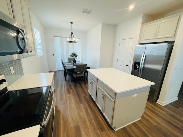 kitchen featuring dark hardwood / wood-style flooring, a notable chandelier, pendant lighting, a kitchen island, and appliances with stainless steel finishes