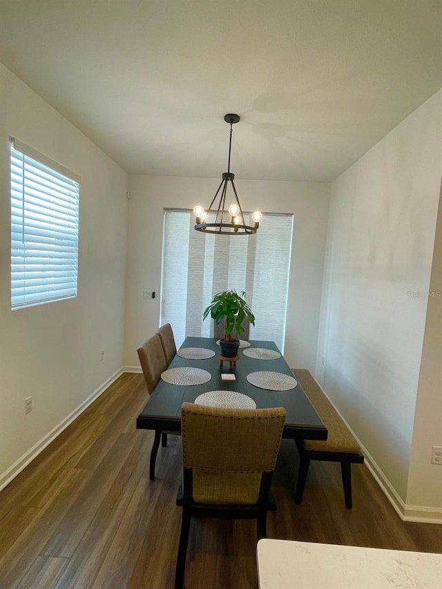 dining space with a notable chandelier and dark hardwood / wood-style flooring