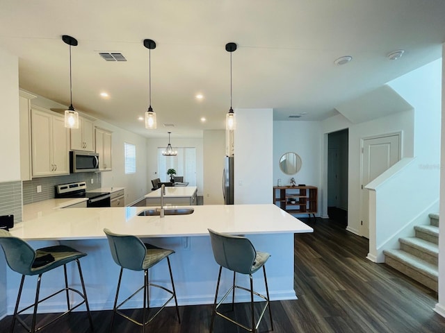 kitchen featuring stainless steel appliances, dark wood-type flooring, sink, decorative light fixtures, and white cabinetry