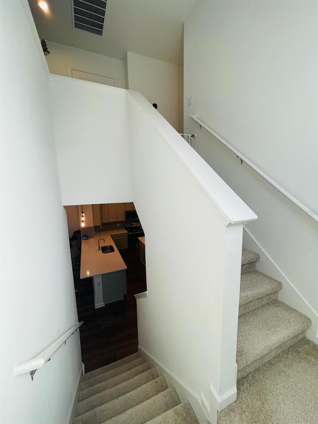 stairway with hardwood / wood-style floors and sink