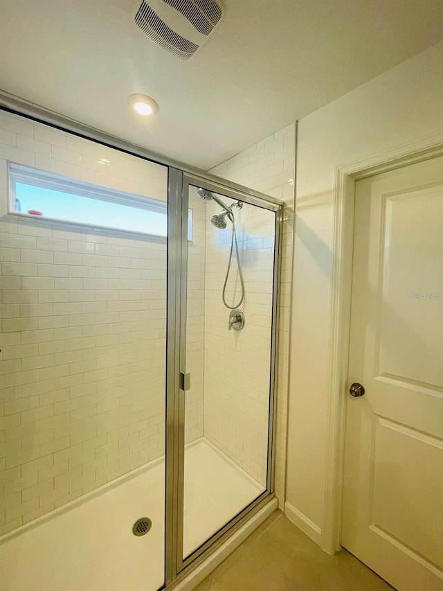 bathroom with tile patterned flooring, a healthy amount of sunlight, and a shower with shower door