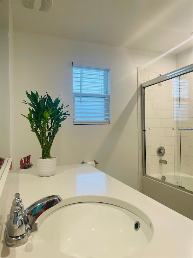 bathroom featuring combined bath / shower with glass door and sink