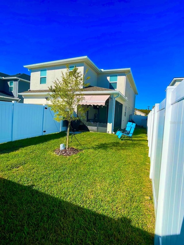 back of property with a lawn and a sunroom