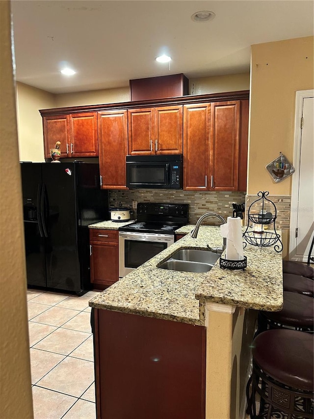 kitchen with a kitchen breakfast bar, backsplash, sink, black appliances, and light tile patterned flooring