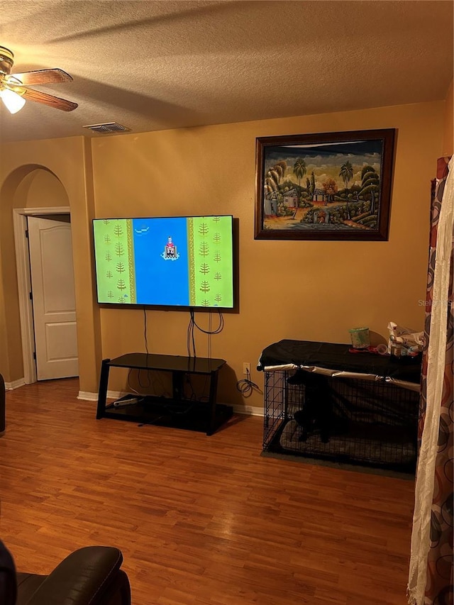 living room featuring hardwood / wood-style floors, ceiling fan, and a textured ceiling