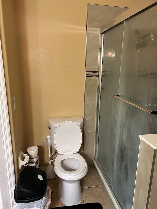 bathroom with tile patterned flooring, a shower with shower door, and toilet