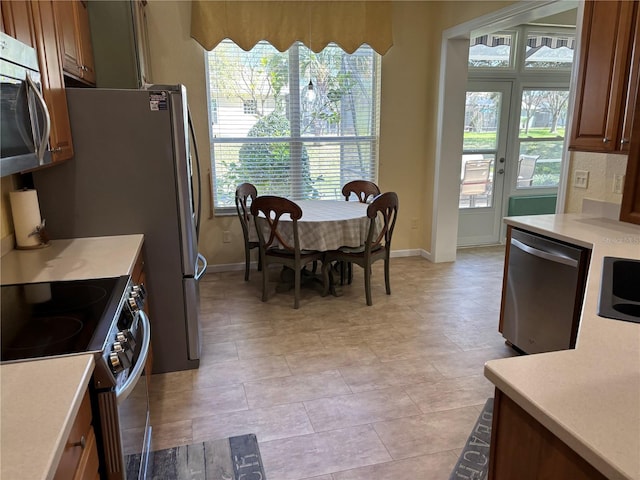 kitchen with a sink, stainless steel appliances, light countertops, and a healthy amount of sunlight