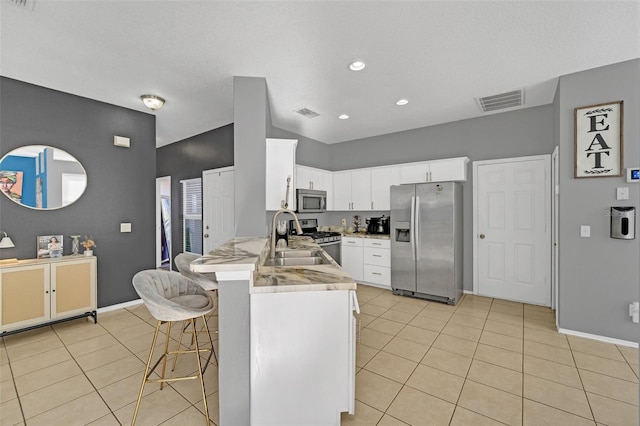 kitchen with white cabinets, sink, appliances with stainless steel finishes, kitchen peninsula, and a breakfast bar area