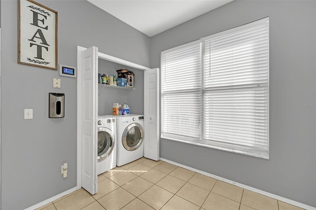 laundry area with washing machine and clothes dryer and light tile patterned floors