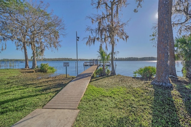 dock area with a lawn and a water view